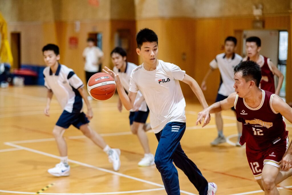 Teen boys playing competitive basketball indoors, showcasing teamwork and agility.