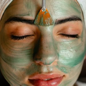 Home Close-up of a woman enjoying a green cosmetic facial mask application at a spa.