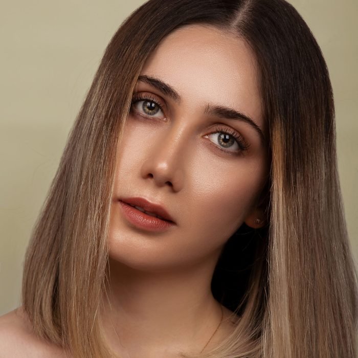 Elegant portrait of a young woman with natural makeup and long bob hairstyle in a studio setting.