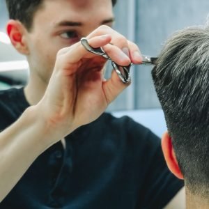 Home Barber skillfully cutting a customer's hair in a contemporary barbershop setting.
