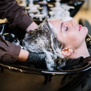 Home Professional hair stylist washing woman's hair in a modern salon setting.