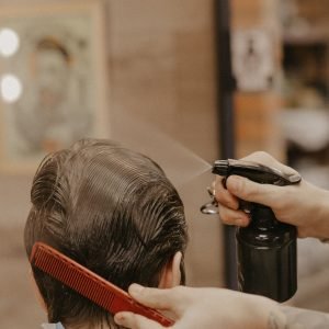 Home Hairdresser using a comb and spray bottle to style hair in a barbershop setting.