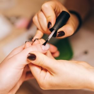 Home Close-up of a manicurist applying nail polish during a professional manicure session.